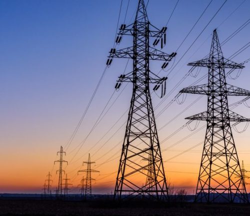 High voltage power line in field at sunset