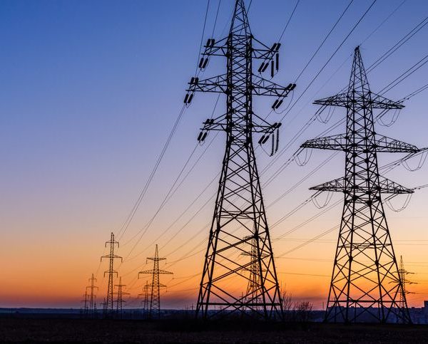 High voltage power line in field at sunset